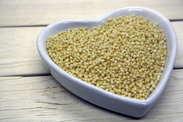 Dry yellow grain millet on a wooden background.