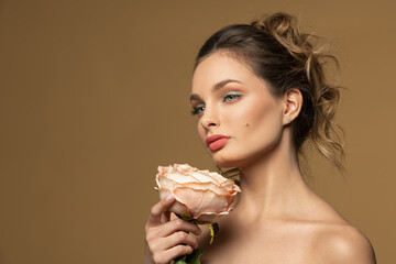 spring beauty girl with a rose looking away on beige background