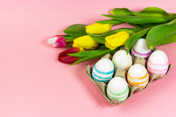 Fototapeta na wymiar Easter painted eggs with tulips on a pink background. Copy space. Easter celebration concept.