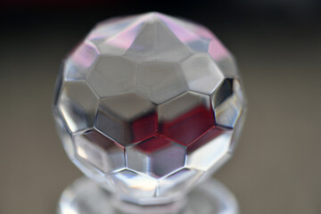 The shiny closure of a crystal carafe. Rhombic structures in a glass ball.