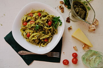 Fettuccine pasta with pesto sauce. Basil and nuts on white background. Italian cuisine. Top view.