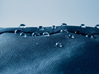 Water drops on waterproof membrane fabric. Detail view of texture of blue waterproof cloth.