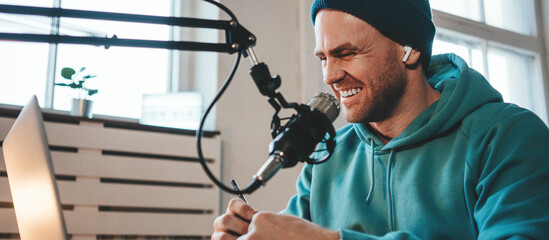 A host streaming his live podcast using microphone and laptop at his homemade broadcast studio