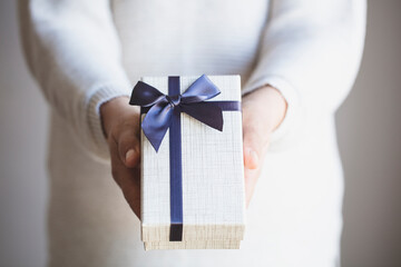 Mature woman with gift box in hand. Giving a special gift in the concept of Mother's Day, Valentine's Day, Birthday, New Year.
