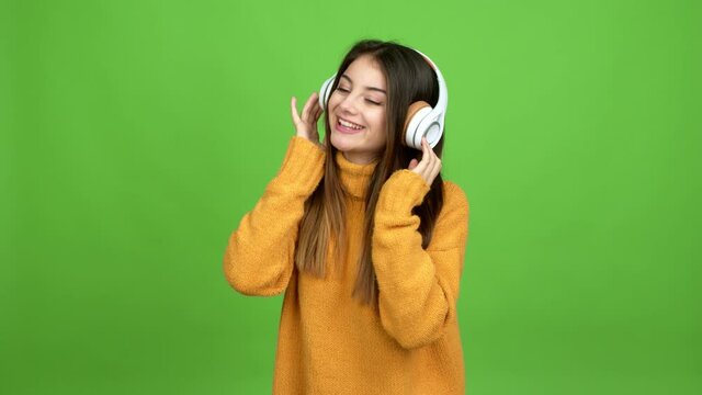 Young caucasian woman listening to music with headphones over isolated background. Green screen chroma key