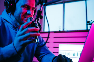 Streamer  broadcasting his live audio show at home studio using stylish cyber punk blue magenta...
