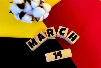 March 14 on wooden cubes on a multi-colored background of yellow, red and black.next to cotton .Spring.Calendar for March .