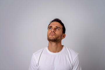 Portrait of a thoughtful man in a white T-shirt looking in the upper right corner