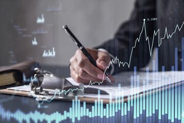 African American businesswoman in formal wear is signing the contract to invest money in stock market. Internet trading and wealth management. Forex and financial hologram chart.