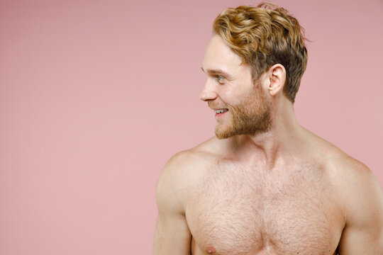 Funny attractive bearded naked young man 20s years old perfect skin standing looking aside isolated on pastel pink color background studio portrait. Skin care healthcare cosmetic procedures concept.