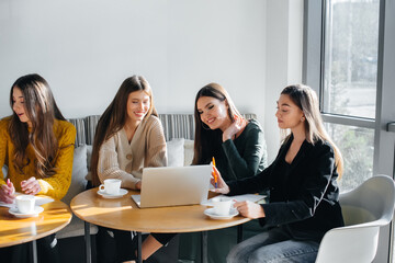 A group of young girls sit in an office at computers and discuss projects. Communication and training online.