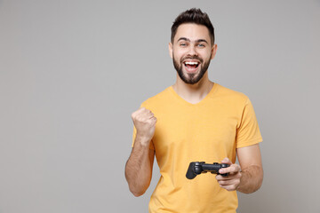 Young caucasian smiling bearded student gamer happy man 20s in casual yellow basic t-shirt play pc...