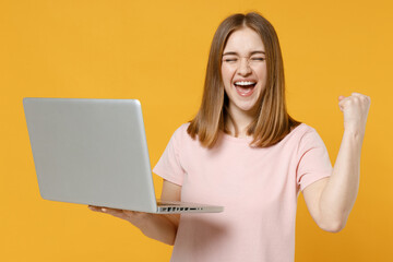 Young freelancer copywriter woman 20s wearing casual basic pastel pink t-shirt hold laptop pc...