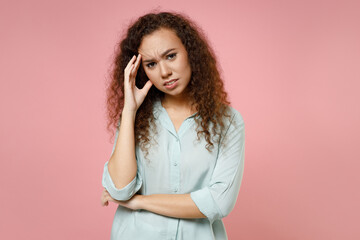 Young black african american puzzled thoughtful pensive sad tired curly depressed woman 20s wearing casual blue shirt looking camera prop up head isolated on pastel pink background studio portrait.