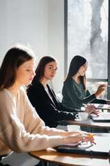 A group of young girls sit in an office at computers and discuss projects. Communication and training online.