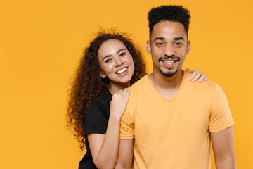 Obraz premium Young happy couple friends together family african smiling lovely woman man 20s wear black yellow t-shirt girlfiend hug boyfriend isolated on orange background studio portrait. Relationship concept.