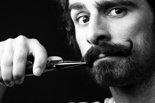 uomo si aggiusta il baffo con una pinza 