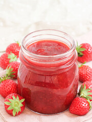 A jar of strawberries jam with its fresh fruits in white isolate background homemade and confectionery concept