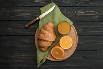 Croissant, orange on a wooden board on a dark wooden background. Breakfast, the beginning of a new...