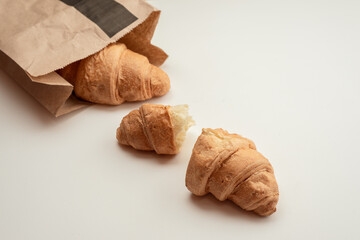 Croissants wrapped in paper bag on a white background. Top view, delicious breakfast, copy space.