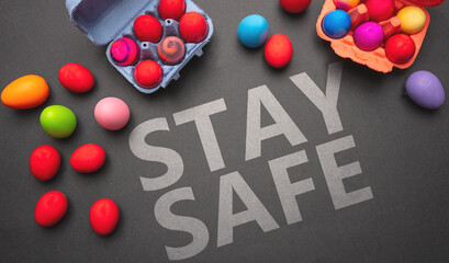 Easter at coronavirus days. Stay safe text message and Easter eggs on grey black color background, top view