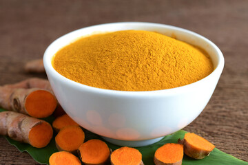 Turmeric powder and fresh turmeric (curcumin) on wooden background,Used for cooking.