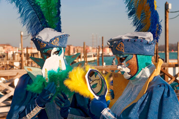 Obraz premium The Carnival of Venice: Molo San Marco, Venice, Italy: masked revellers pose with looking-glasses in front of the Basin of St Mark, on a gondola landing stage
