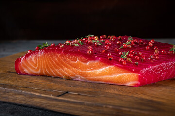 Smoked salmon in one piece with herbs and berries in Scandinavian style on a wooden board