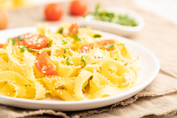 Reginelle semolina pasta with tomato, eggs, sesame and microgreen sprouts on a white wooden background. Side view, selective focus.