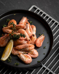 Shrimp lunch with lemon on black background. Seafood plate of Shrimp in asian restaurant. Template for design of restaurant menu and Web publications. Vertical format.