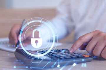 A businessman computing probability of risks in cyber security protection using calculator. Padlock Hologram icons over the working desk. Formal wear.