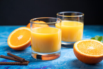 Glass of orange juice on a black and blue background. Side view, close up.