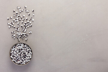 Legumes in bowl and scattered in the background, white and purple beans in a plate on a gray background, top view, copy space