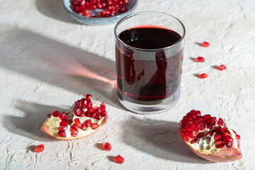 Glass of pomegranate juice on a white concrete background. Hard light, side view.