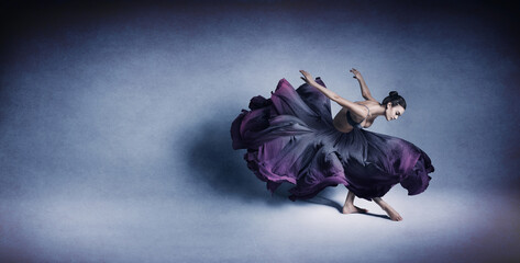 Graceful woman dancing in flowing dark blue dress