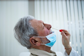 Close up of an old man getting PCR nasal test at doctor's office during corona virus epidemic.
