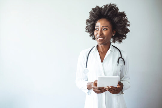 Friendly African American female doctor at the hospital looking at the camera and smiling. Portrait of confident medical professional is wearing lab coat and stethoscope