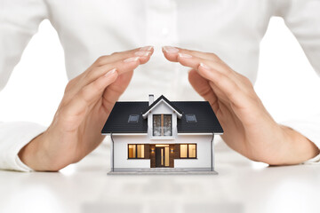 Home protection concept, close up of female hands shielding modern house