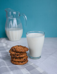 Fresh homemade milk in a glass and homemade oatmeal cookies on a white and blue background. Selective focus of oatmeal cookies. Healthy breakfast and weight loss concept. Breakfast in the village