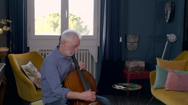 Senior woman filming her husband playing cello with smart phone