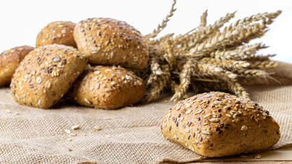 Freshly baked bread. Fresh loaf of rustic traditional bread with wheat grain ear or spike plant on linen texture background. Rye bakery with crusty loaves and crumbs. Healthy Food concept.