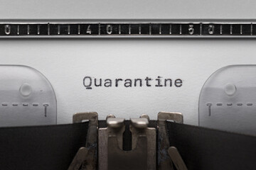 Typing text QUARANTINE on vintage manual typewriter. Close up of writes word on white paper. Shot...