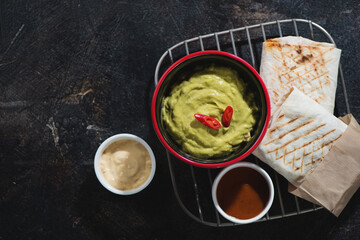 Metal cooling rack with shawarma or shaurma and dips, top view on a dark brown stone background, studio shot, copy space