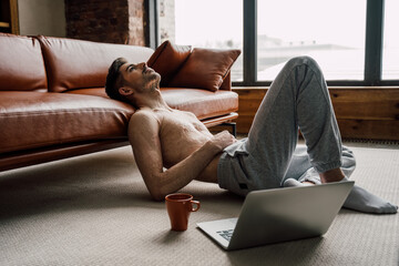 Man with scars at the skin after burn relaxing while using laptop and drinking tea