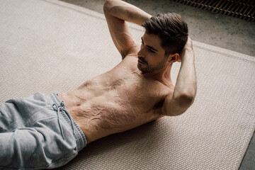 Man with scars at the skin after burn practicing abdominal crunches, rock press exercise