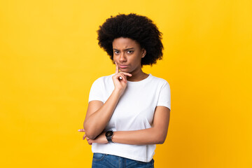 Fototapeta na wymiar Young African American woman isolated on yellow background and thinking