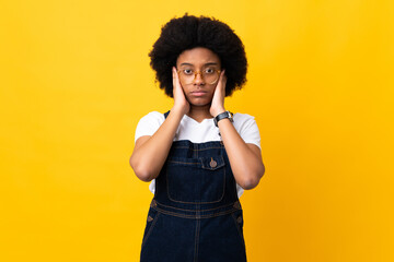 Young African American woman isolated on yellow background frustrated and covering ears