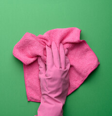 female hand in a pink rubber glove holds a pink cleaning rag on a purple background