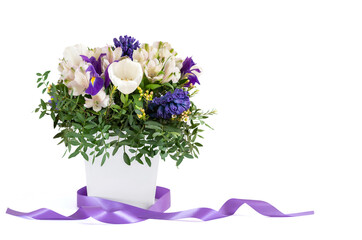 Beautiful spring bouquet in a box with a purple ribbon isolated on a white background. Greeting card. Copy space. Mothers Day concept.