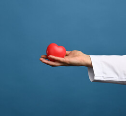 medic in a white coat holds a red heart on a blue background